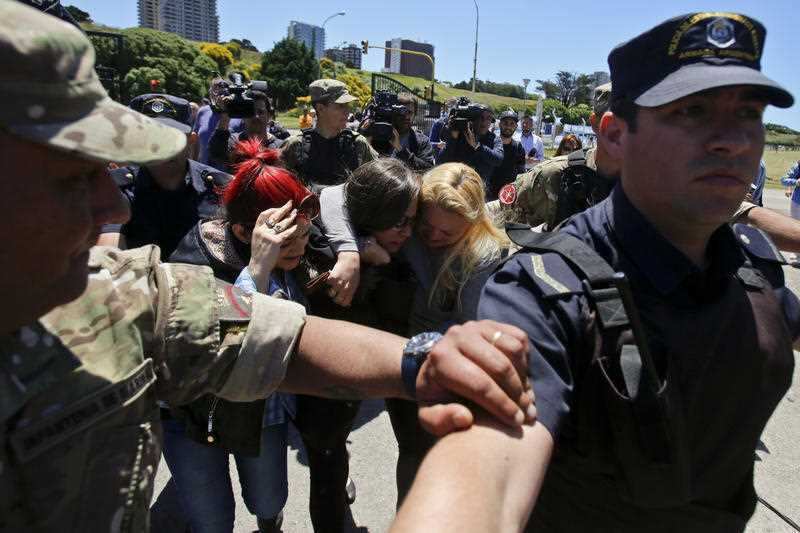 Police and soldiers form a protective circle around distraught relatives of missing submarine crew member Celso Oscar Vallejo