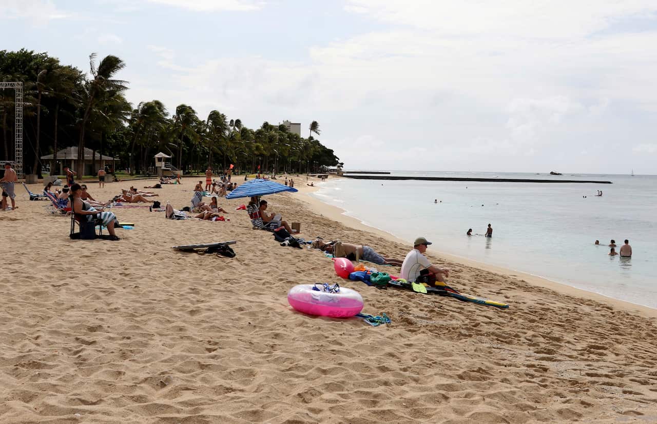 People sit on the beach and swim in the Waikiki area of Honolulu on December 1, 2017.