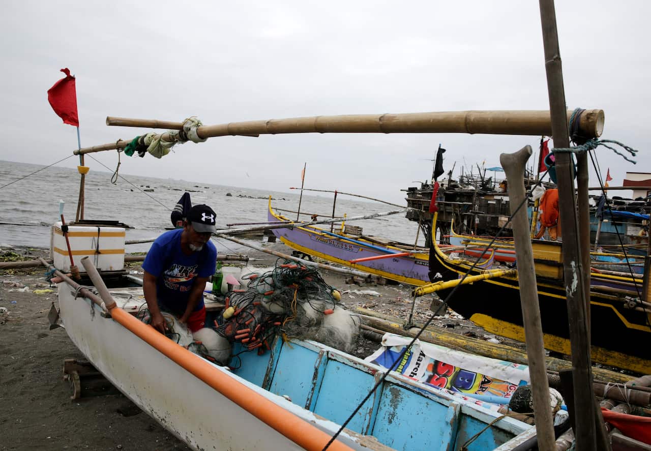 A Filipino fisherman secures a boat at a coastal village in Cavite city.