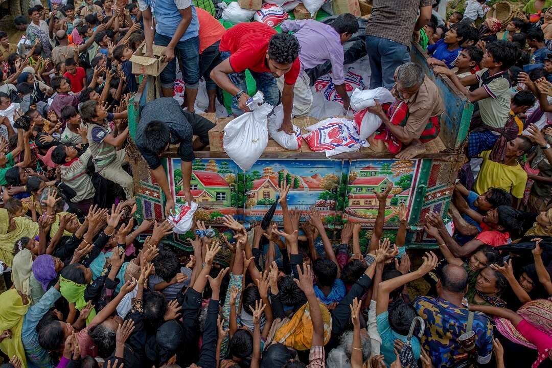 Rohingya Muslims, who crossed over from Myanmar into Bangladesh, reach out for food distributed by aid agencies in 2017.