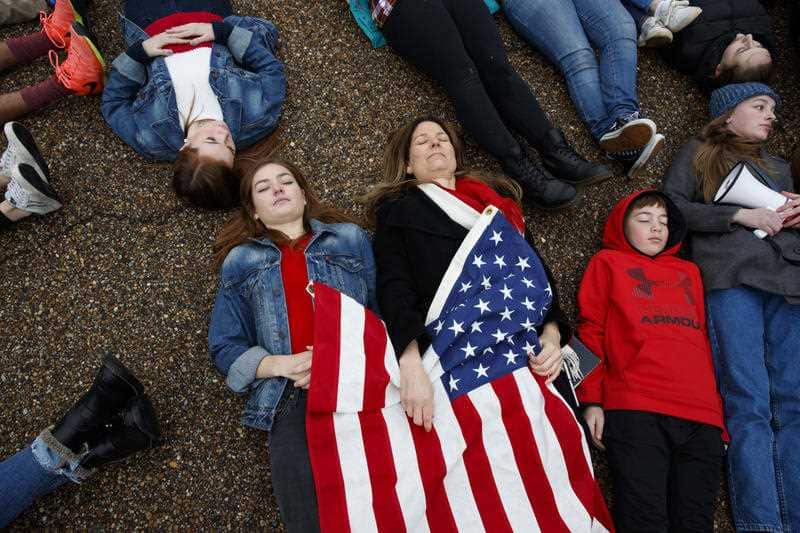 Abby Spangler and her sixteen year-old daughter Eleanor Spangler Neuchterlein hold hands as they participate in a "lie-in" during a gun reform protest