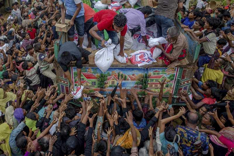 Rohingya Muslims, who crossed over from Myanmar into Bangladesh, stretch their arms out to collect food items distributed by aid agencies.