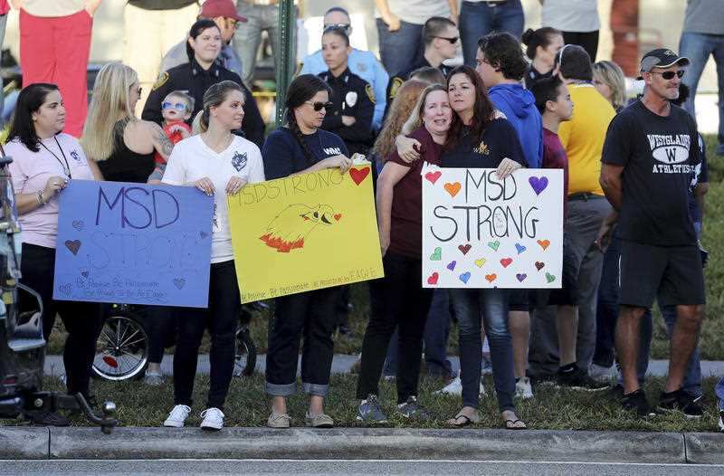 Supporters hold signs as students head back to classes at Marjory Stoneman Douglas High School in Parkland.