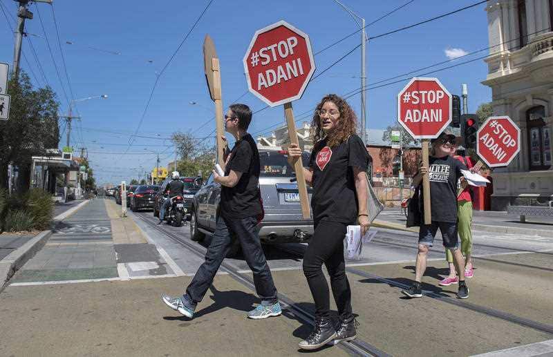 Stop Adani protesters hand out leaflets and sing protest songs along High Street, Northcote, Melbourne, Saturday, March 3, 2018.