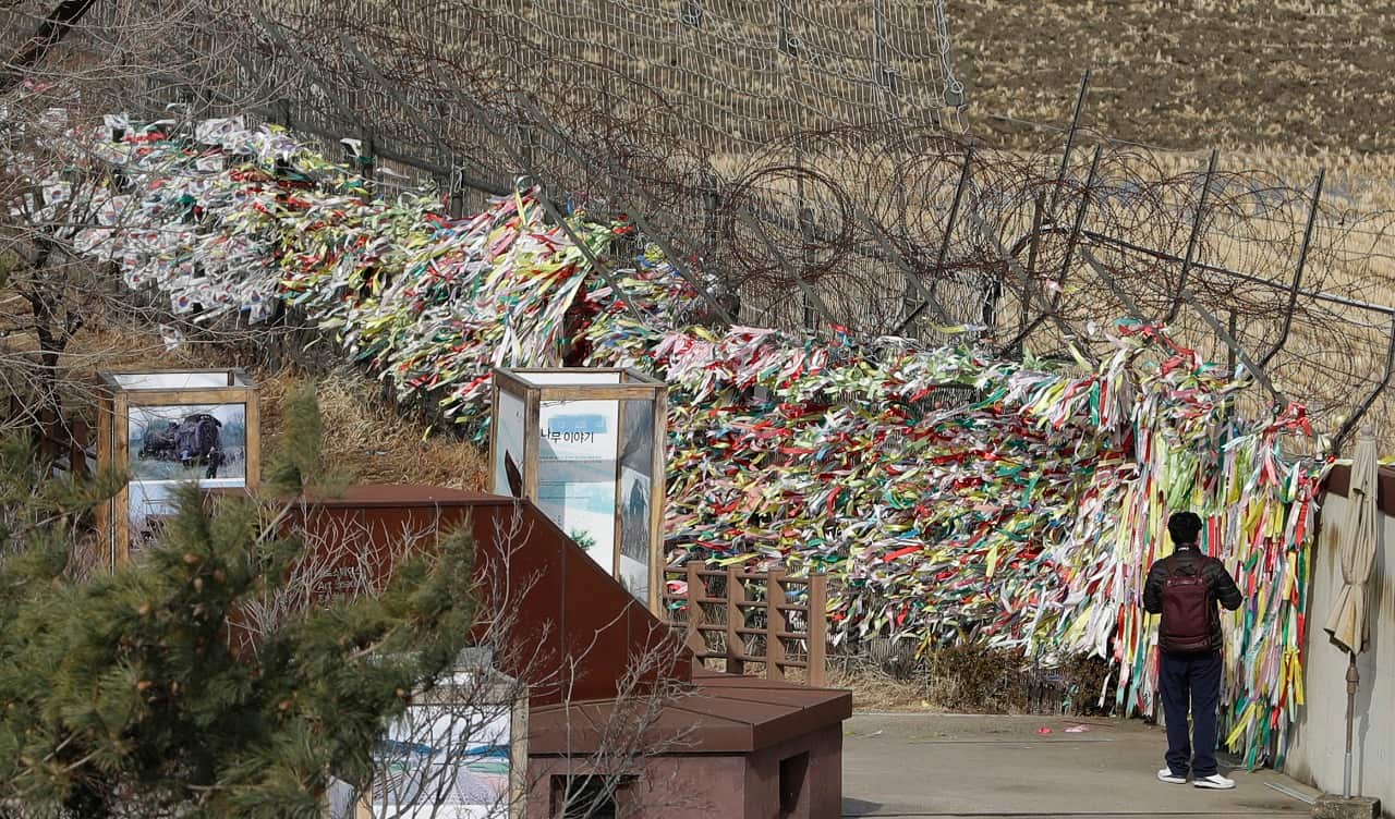 A man walks near the wire fence decorated with ribbons wishing for reunification and peace of the two Koreas at the Imjingak Pavilion in Paju, South Korea.