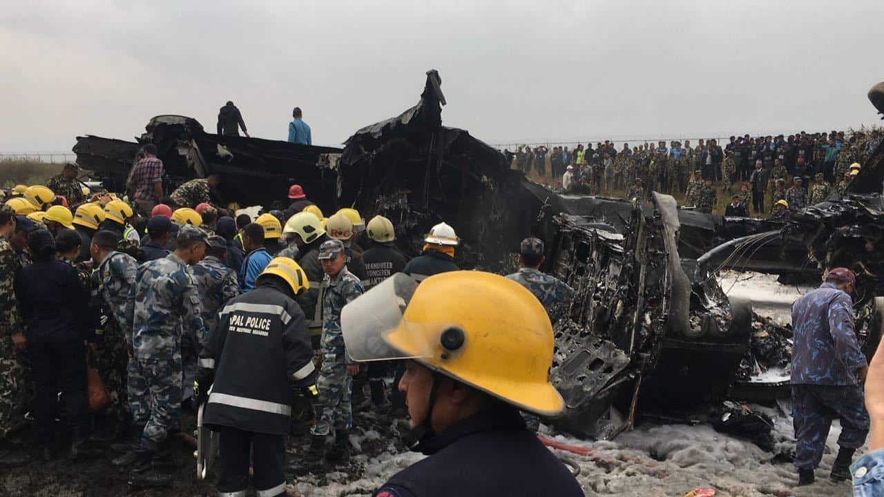 Nepalese rescuers stand near a passenger plane from Bangladesh that crashed at the airport in Kathmandu, Nepal. (AAP)