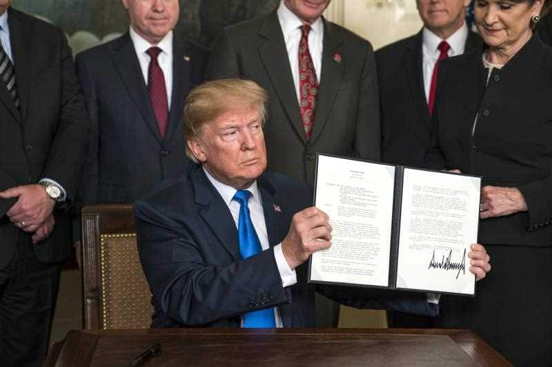 US President Donald J. Trump (C) raises a presidential memorandum targeting what the White House termed 'China's economic aggression' in the Roosevelt Room of the White House in Washington, DC, USA, 22 March 2018.