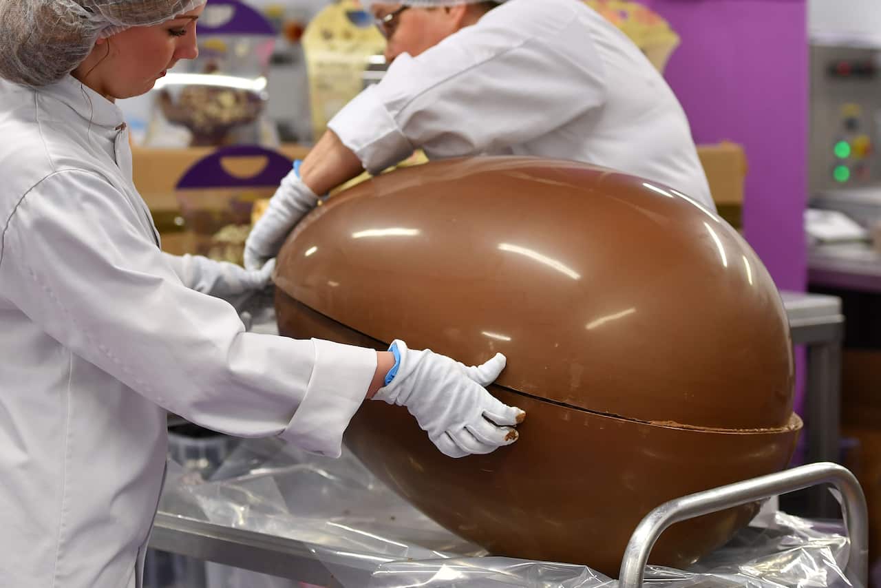 Chocolatiers join two halves of a giant chocolate egg at Cadbury World in Birmingham in 2018.