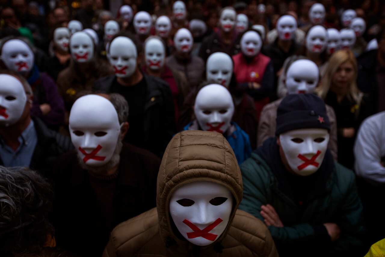 People wear white masks in support of Catalonian politicians jailed on charges of sedition. 
