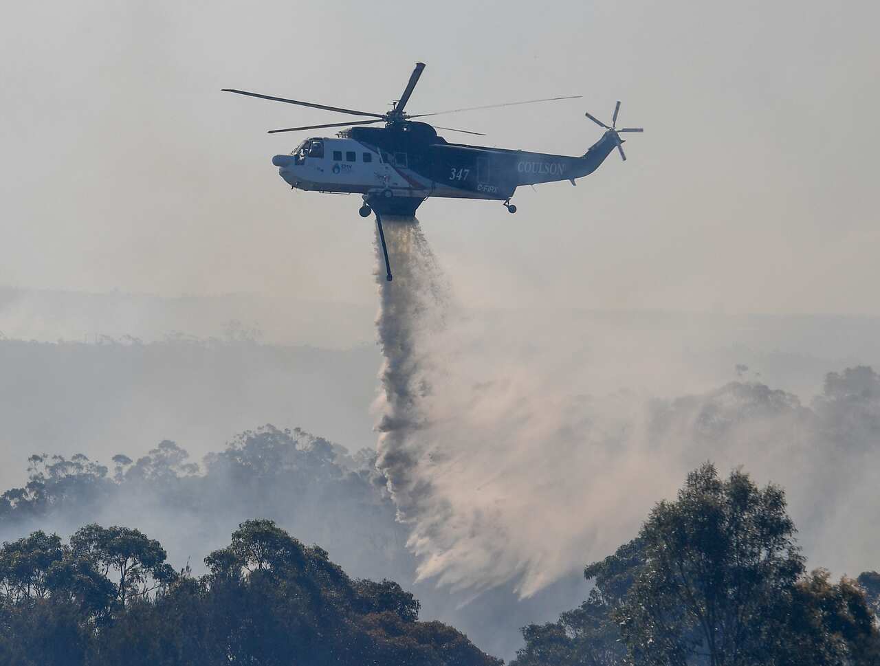 Aerial fire bombing aircraft are seen to control spot fires over Barden Ridge in Sydney.
