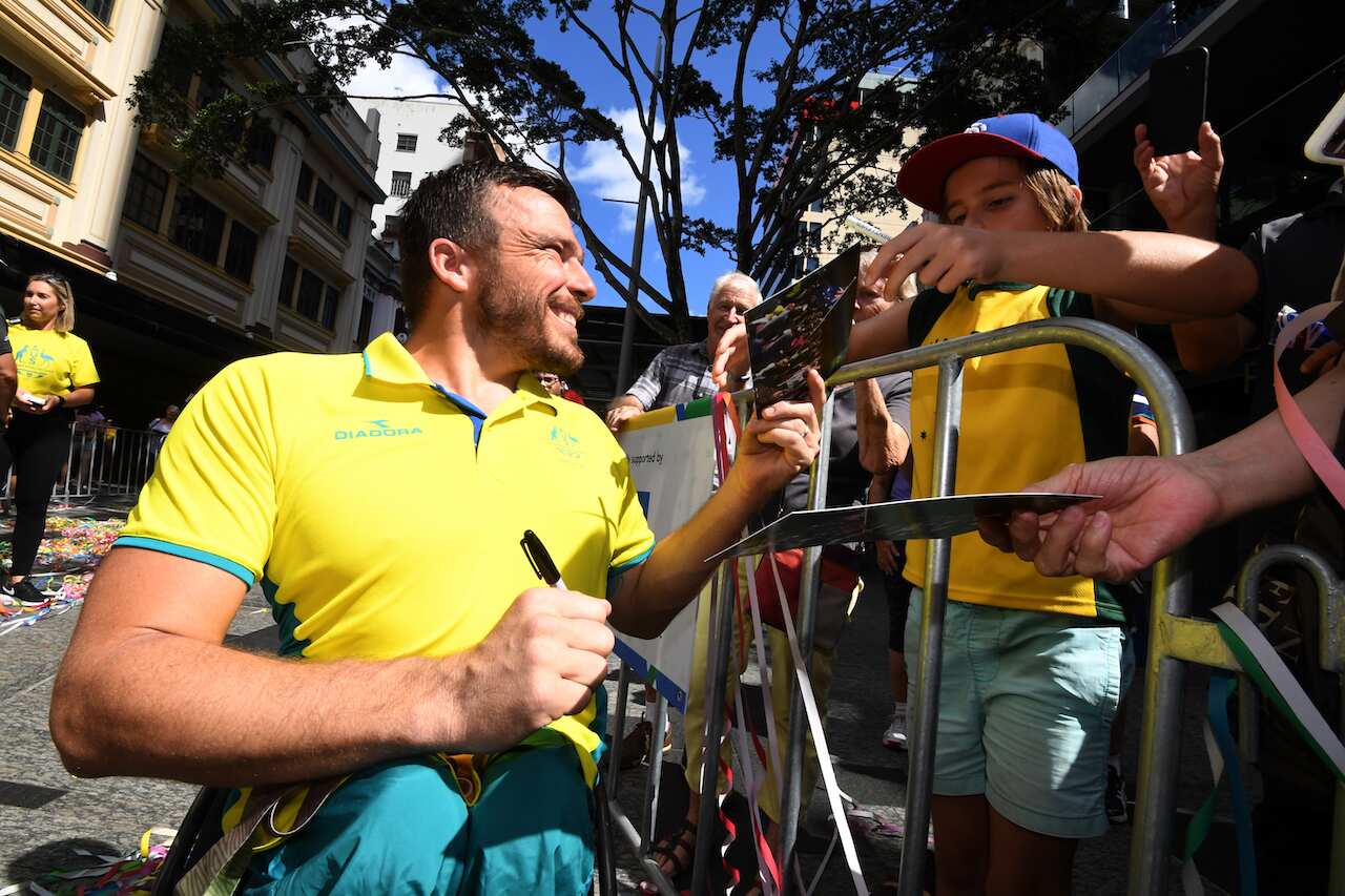 Commonwealth Games wheelchair race gold medalist Kurt Fearnley signs autographs during a street parade to honour the games' athletes through central Brisbane