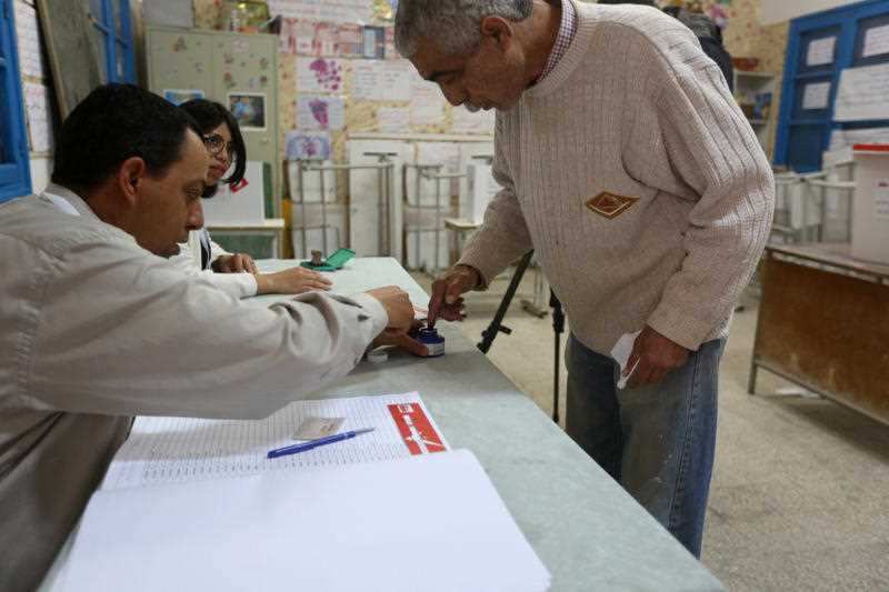 A Tunisian dips his finger in ink before casting his vote at a polling station in Ben Arous, near the Tunisian capital Tunis