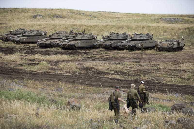 Israeli soldiers walk past tanks in the Israeli-controlled Golan Heights, near the border with Syria, Thursday, May 10, 2018.