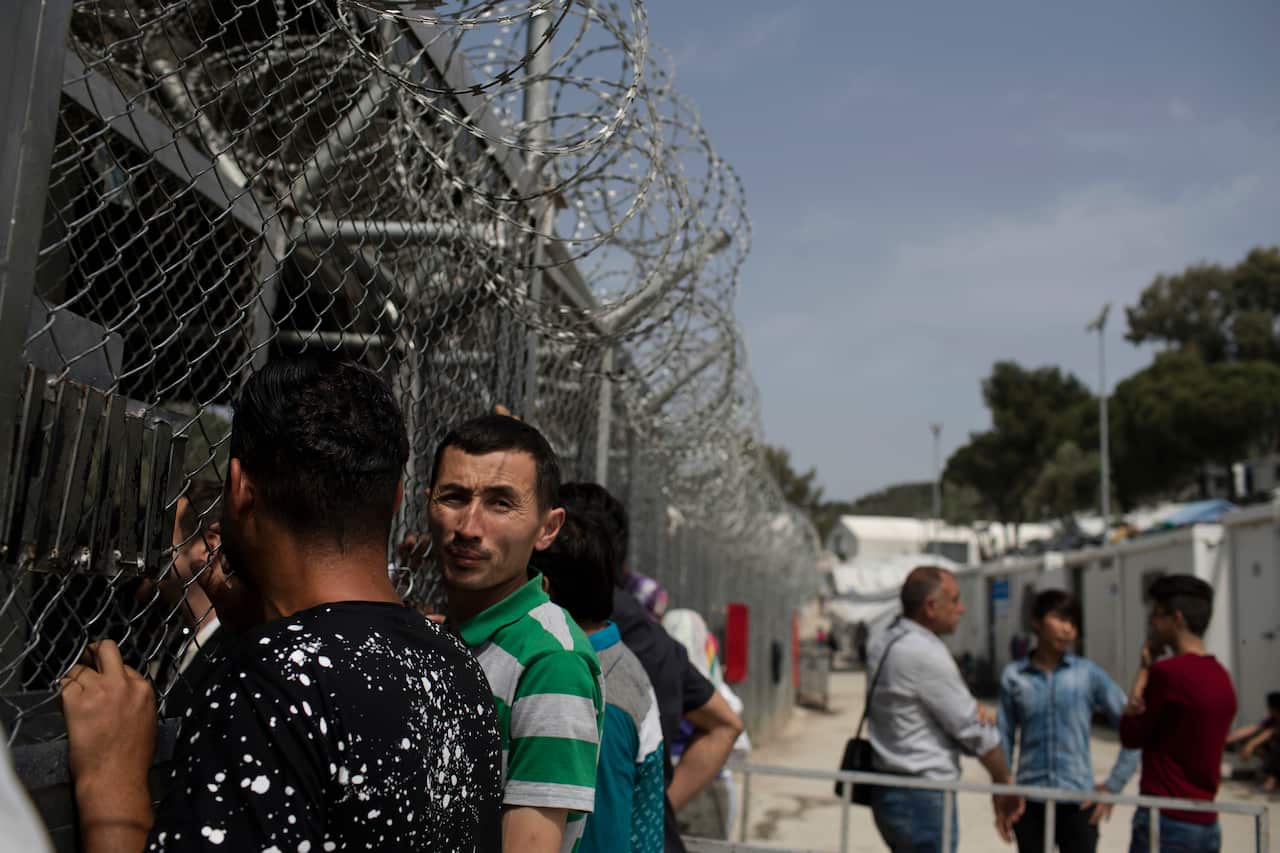 Refugees wait outside the European Asylum Support Service offices inside the camp of Moria on the island of Lesbos.