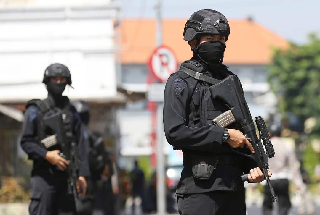 Officer stand guard outside the local police headquarters following the attack in Surabaya.