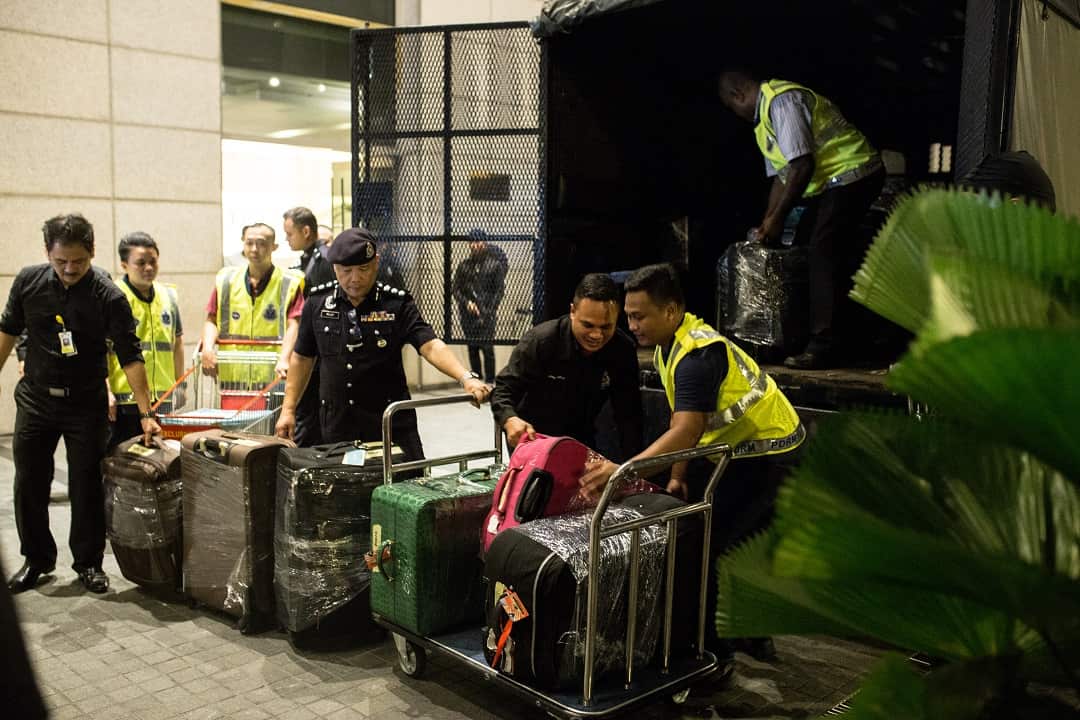 Police load bags into a vehicle following a raid of former prime minister Najib Razak's residence.