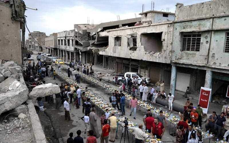 Mosul residents eat the Iftar meal to break their fasting amid the rubble of buildings in the old city of Mosul