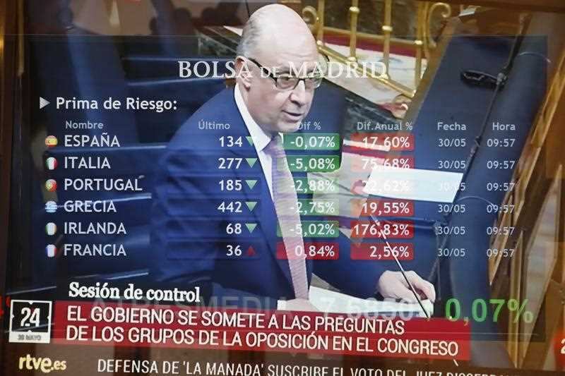 Spanish Treasure Minister, Cristobal Montoro, and a screen displaying several European risk premium figures at Madrid Stock Exchange Market.