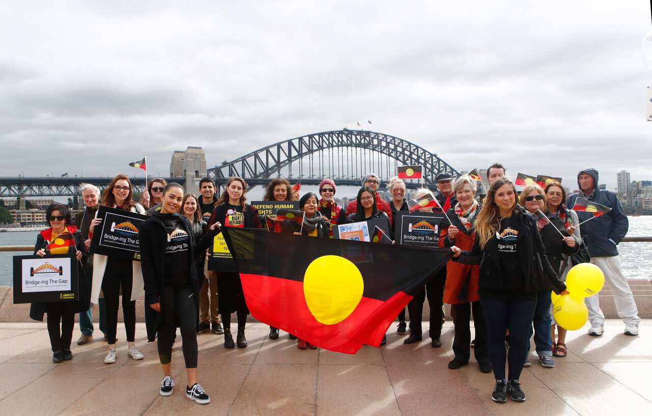 Demonstrators pose for a photograph with the Aboriginal Flag in Sydney