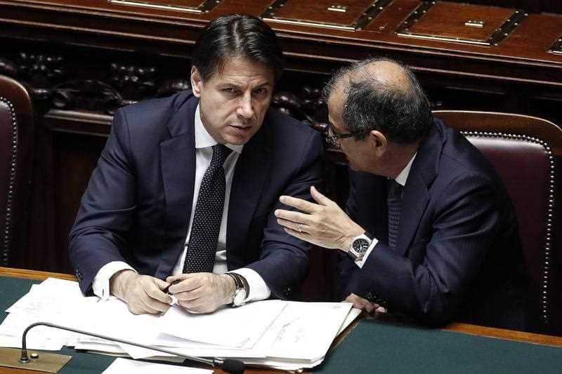 Italian premier Giuseppe Conte, left, and Italian Economy Minister Giovanni Tria talk at the Lower House, ahead of a confidence vote on the government program, in Rome, Wednesday, June 6, 2018. 