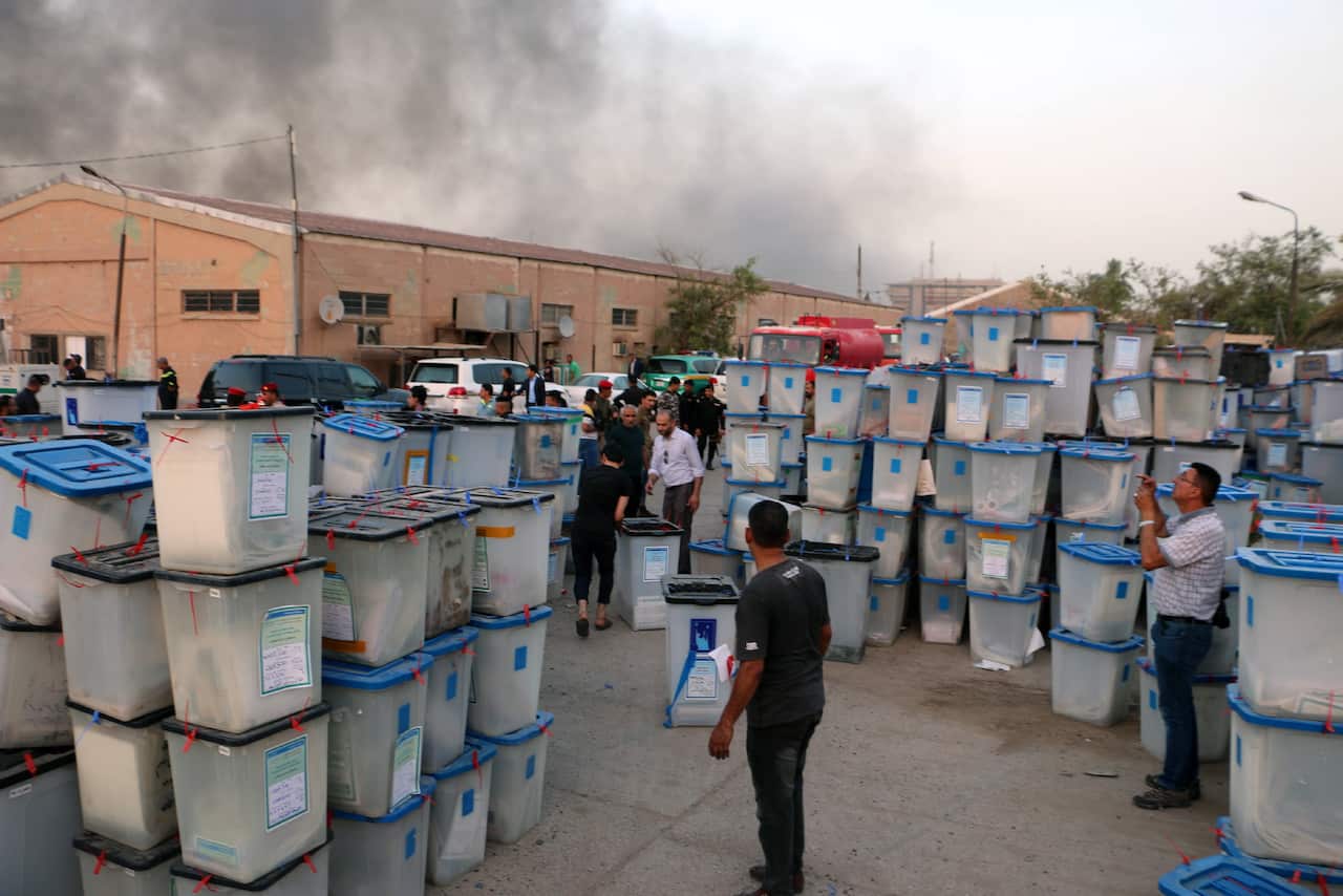Iraqi firefighters and police officers try to extinguish fire at a warehouse in central Baghdad, Iraq on 10 June 2018