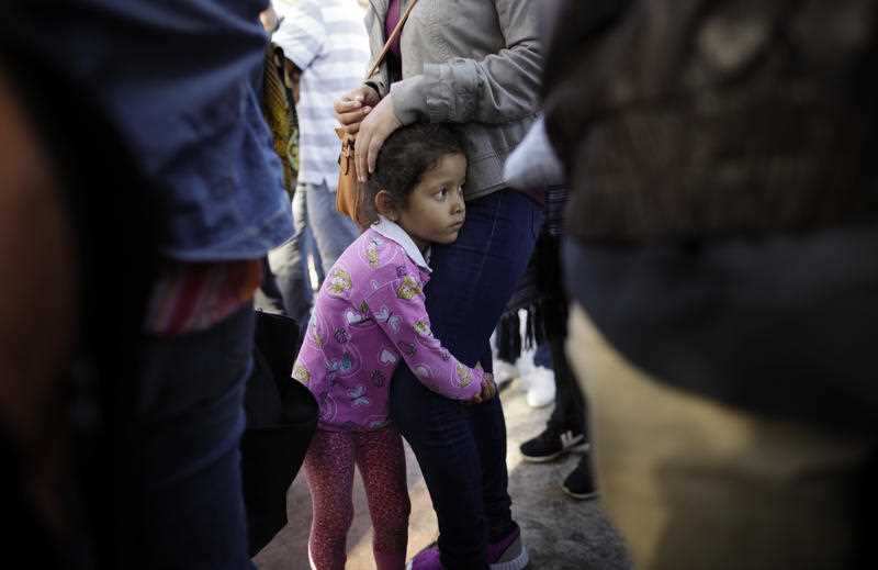 A child holds on to her mother as they wait with other families to request political asylum in the United States
