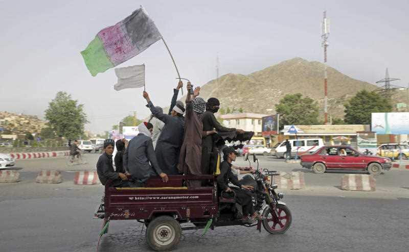 Taliban fighters and their supporters carry a representation of the Afghan and Taliban flag, June 17, 2018.