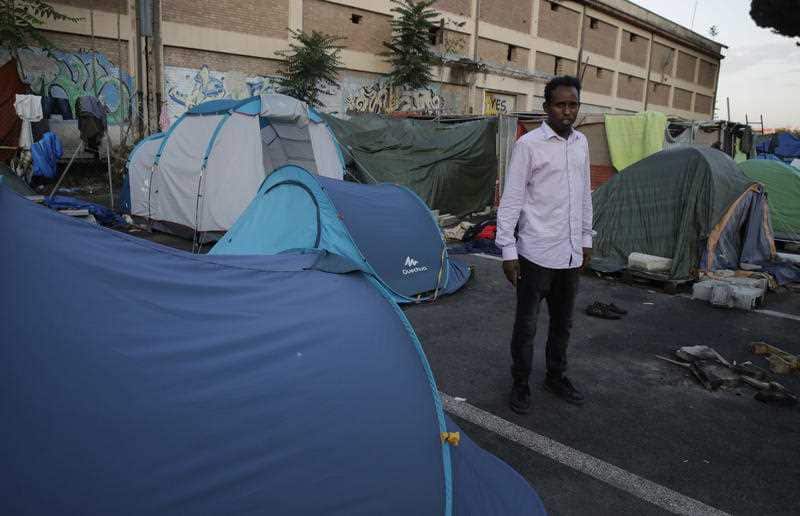 An asylum seeker from the Horn of Africa sits in a tented camp set up by the Baobad aid group, on the outskirts of Rome, Tuesday, June 19, 2018.