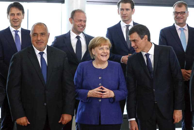 German Chancellor Angela Merkel, center, speaks with Spanish Prime Minister Pedro Sanchez, right, as they pose for a group photo at an informal EU summit on migration at EU headquarters in Brussels, Sunday, June 24, 2018.