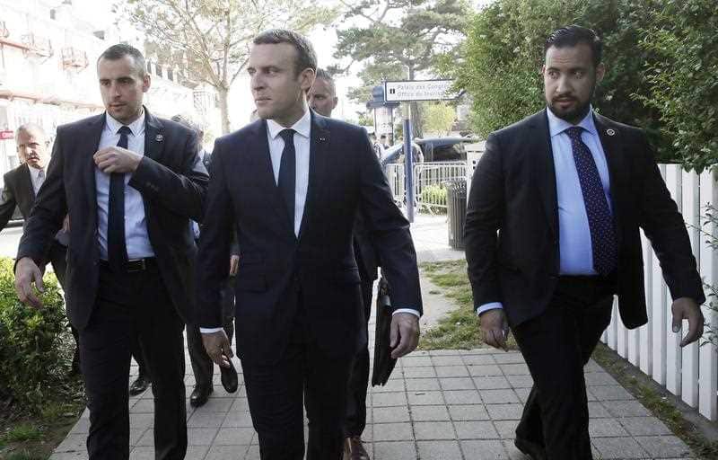 French President Emmanuel Macron (C) flanked by security staff Alexandre Benalla (R) leaves his home.