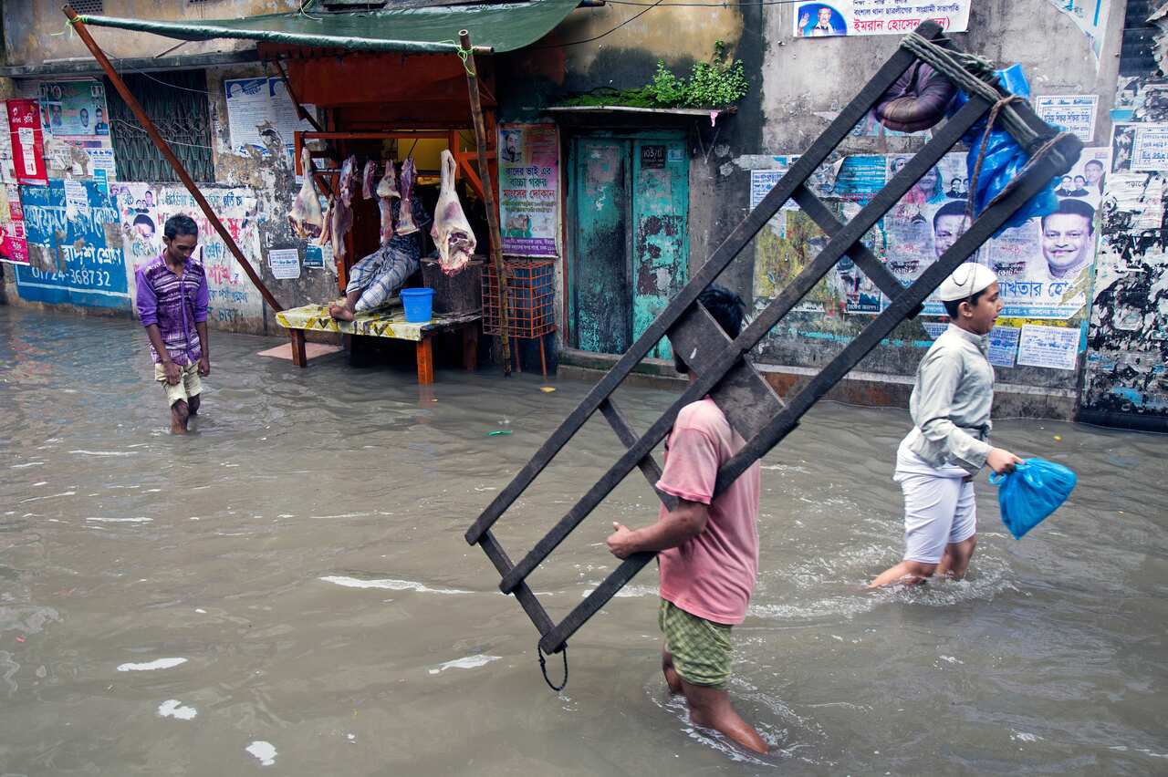 epa06907869 Bangladeshi people walk on the street submerged by rainwater in Old Dhaka city, Bangladesh, 24 July 2018. Heavy monsoon rains flooded parts of the capital.  EPA/MONIRUL ALAM