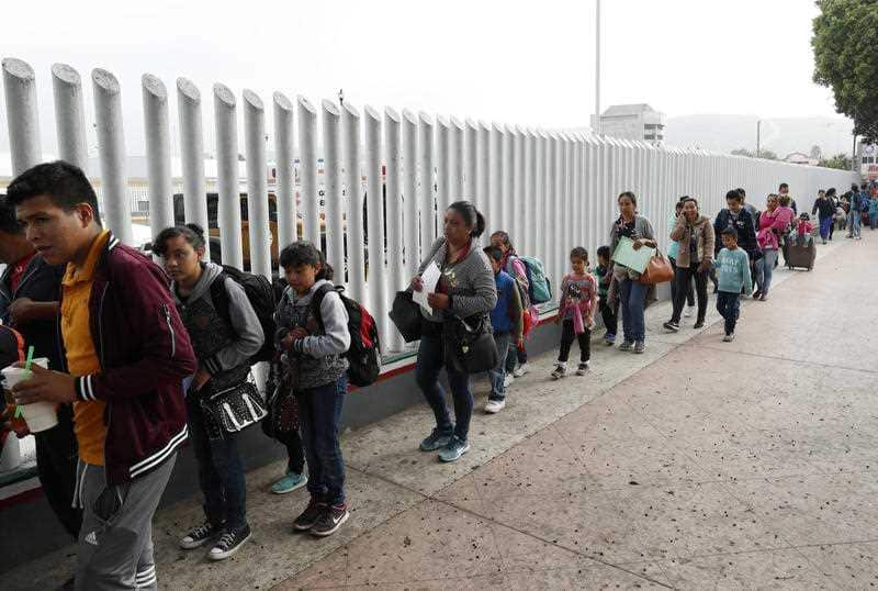 People line up to cross into the United States to begin the process of applying for asylum Thursday, July 26, 2018, near the San Ysidro port of entry in Tijuana, Mexico.