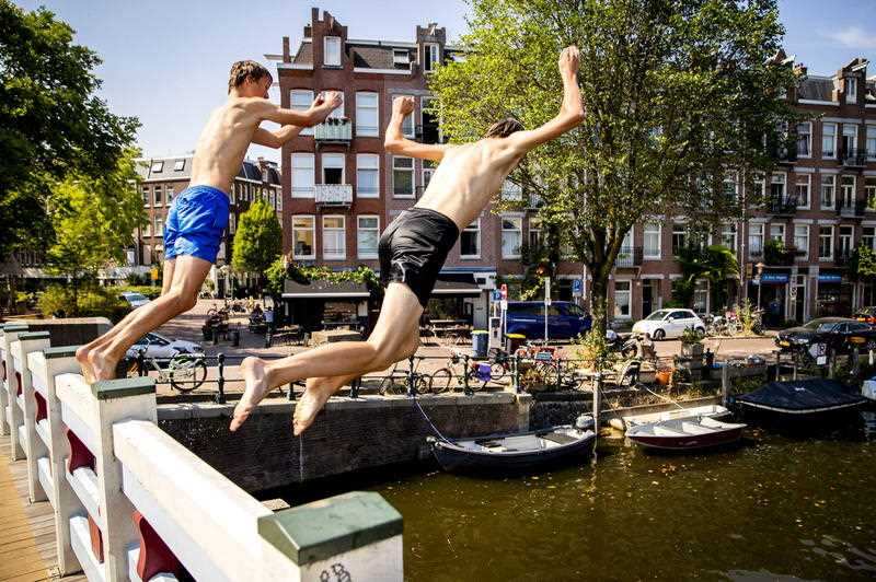 Two boys jump in the Kattensloot canal in Amsterdam, the Netherlands, 27 July 2018, during the first heatwave in three years.