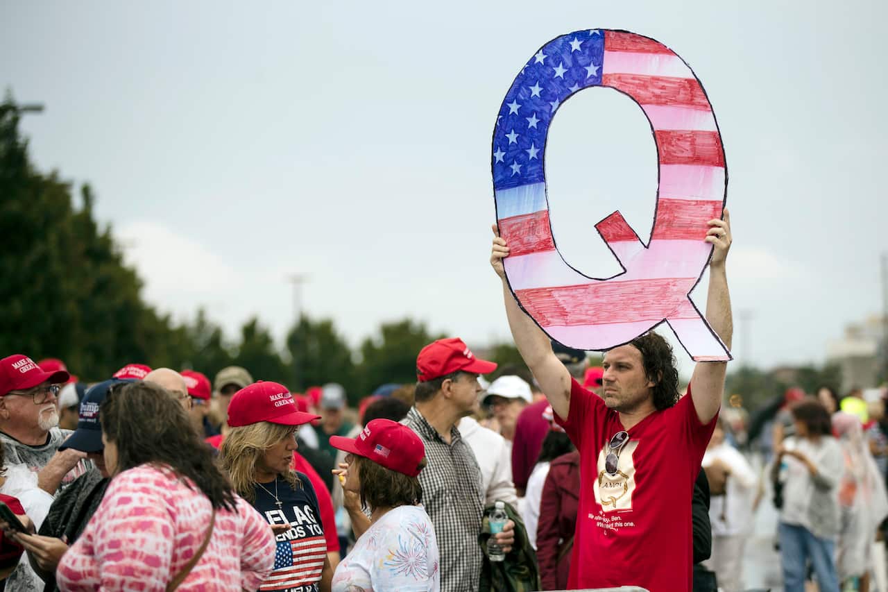 A man holds a Q sign at a Trump rally.