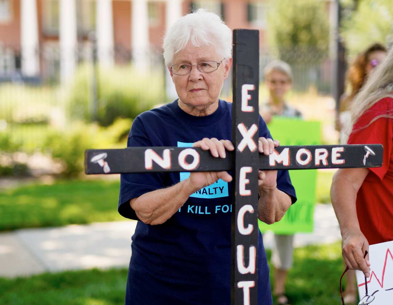 A Nebraska woman holds on to a cross reading "No More Executions" as she pickets with others against the death penalty.
