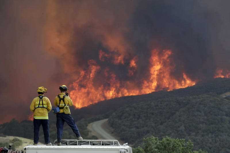 A fire crew from San Luis Obispo County keeps an eye on an advancing wildfire from the perimeter of a residence in Lakeport, California