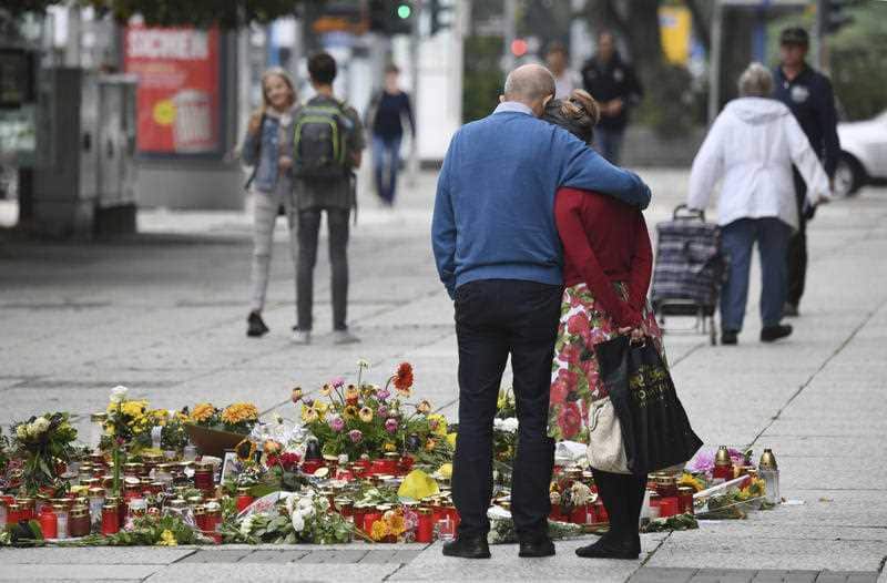 Two people stay next to candles and flowers in Chemnitz, Germany.