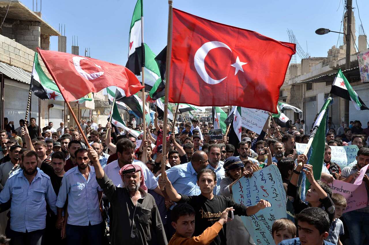 Syrians from the rebel-held northern city of Idlib wave the flag of the opposition as they gather for an anti-government demonstration in Idlib.