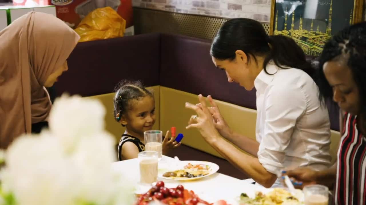 Duchess of Sussex playing with a child while cooking with women in the Hubb Community Kitchen at the Al Manaar Muslim Cultural Heritage Centre in West London.