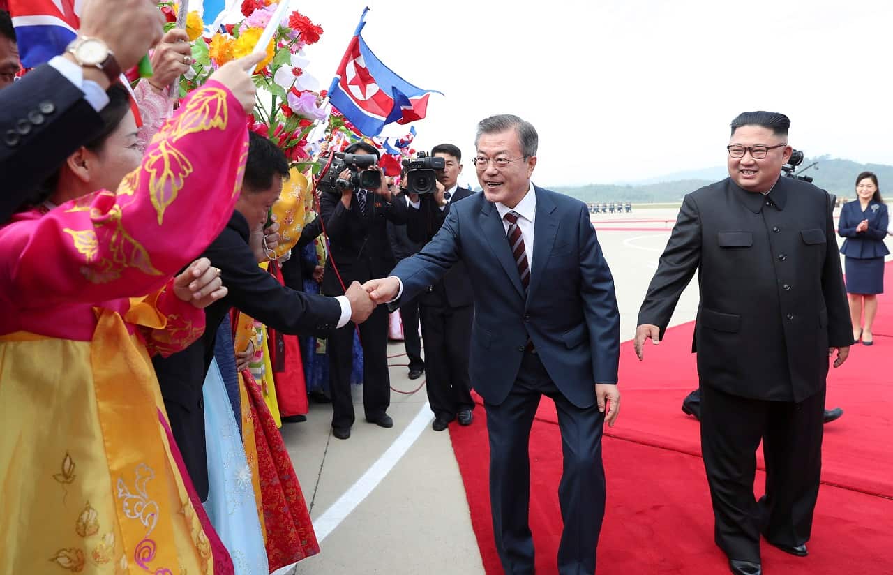 South Korean president Moon Jae-in is greeted by North Korean people beside North Korean leader Kim Jong-un.