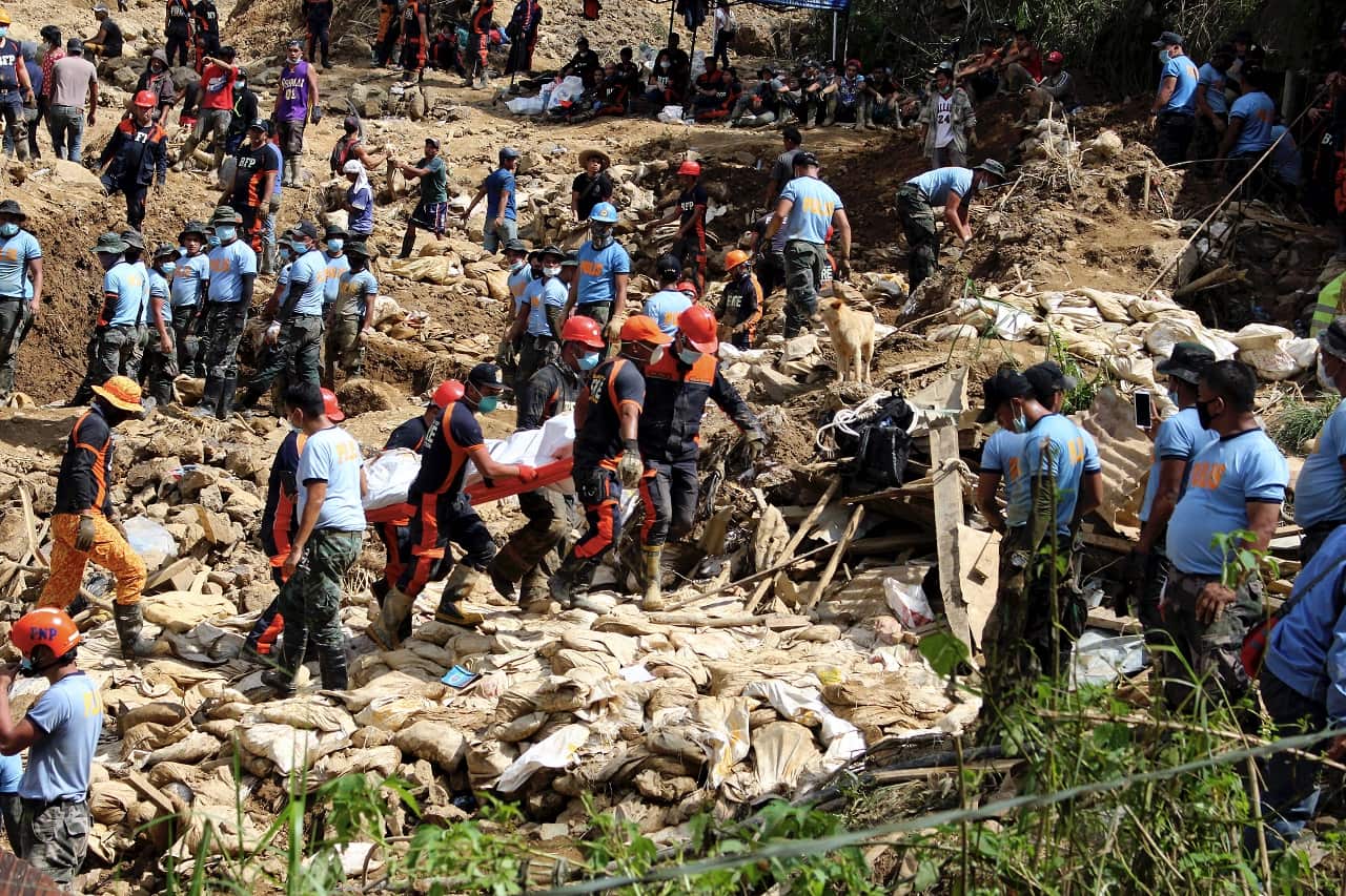 Rescuers carry a body during rescue and retrieval operation for landslide victims caused by Typhoon Mangkhut in the Philippines.