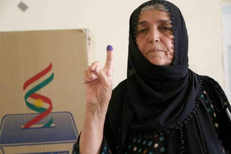A Kurdish woman in traditional clothes shows her ink-marked finger after casting her vote in the Kurdistan parliamentary election at a polling station in Erbil, the capital of the Kurdistan Region in Iraq, 30 September 2018.