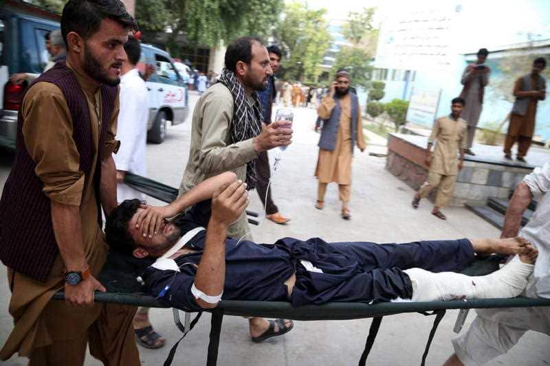 People carry a man, who was injured in a suicide bomb attack at an election campaign in Kama district,