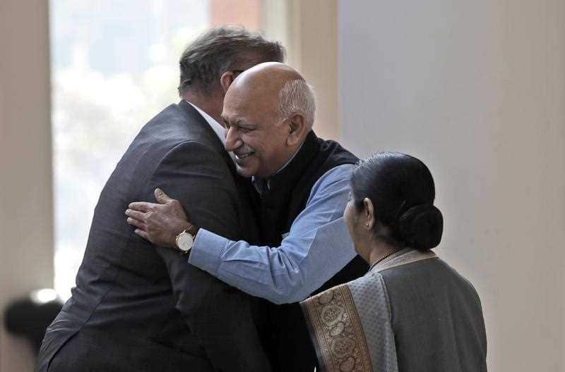 Indian Junior Foreign Minister M.J. Akbar, center, hugs Finland's Foreign Minister Timo Soini in New Delhi, India