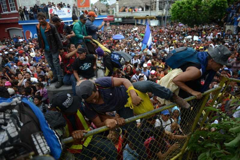 Honduran migrants climb a border fence, in Tecun Uman, Guatemala, Friday, Oct. 19, 2018. 