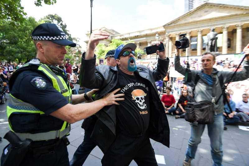 A man wearing a 'Make Australia Great Again' cap tries to disrupt speeches during a refugee rally in Melbourne.