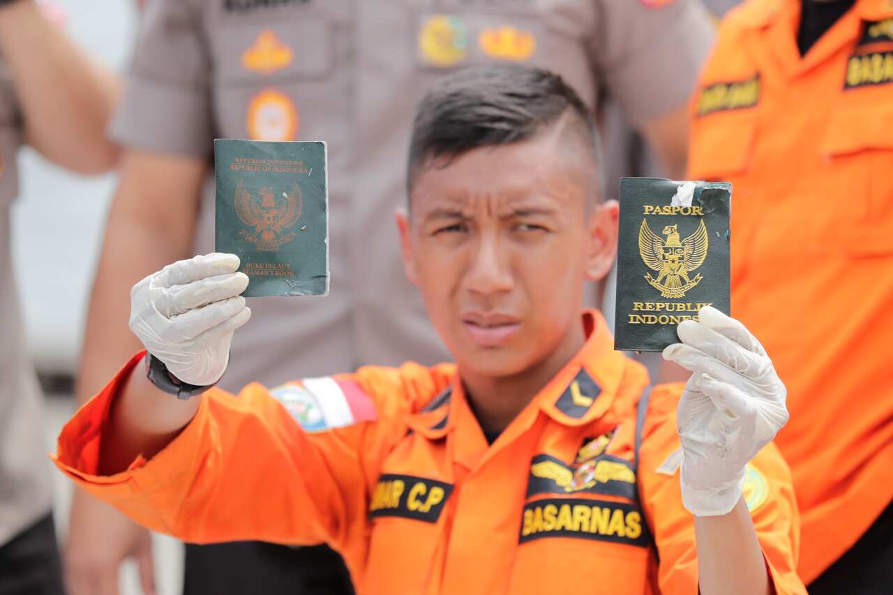 An Indonesian rescuer shows passports belonging to passengers from the Lion Air plane crash.