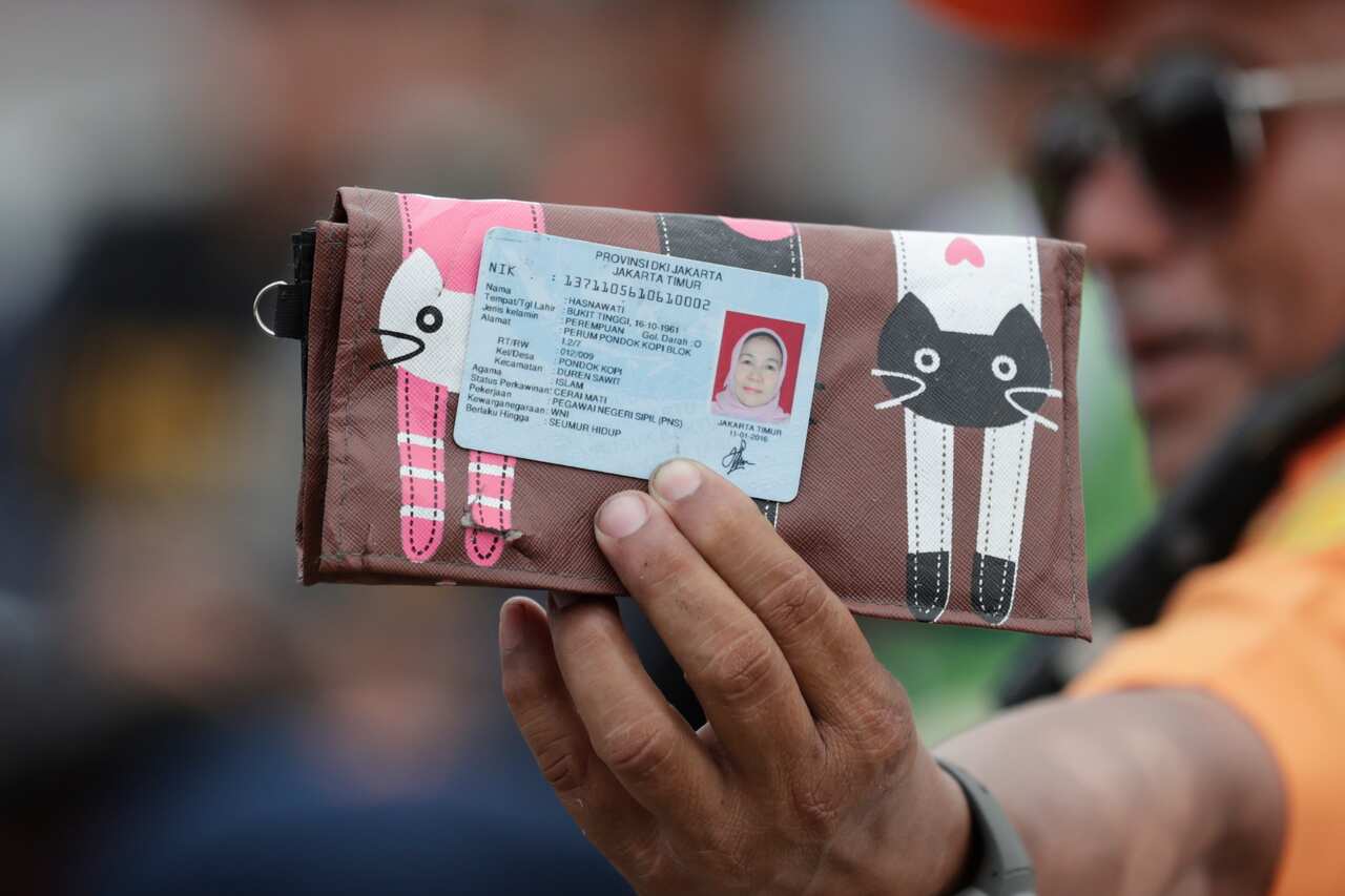 An Indonesian rescuer shows an identity card belonging to a passenger from the Lion Air plane crash.