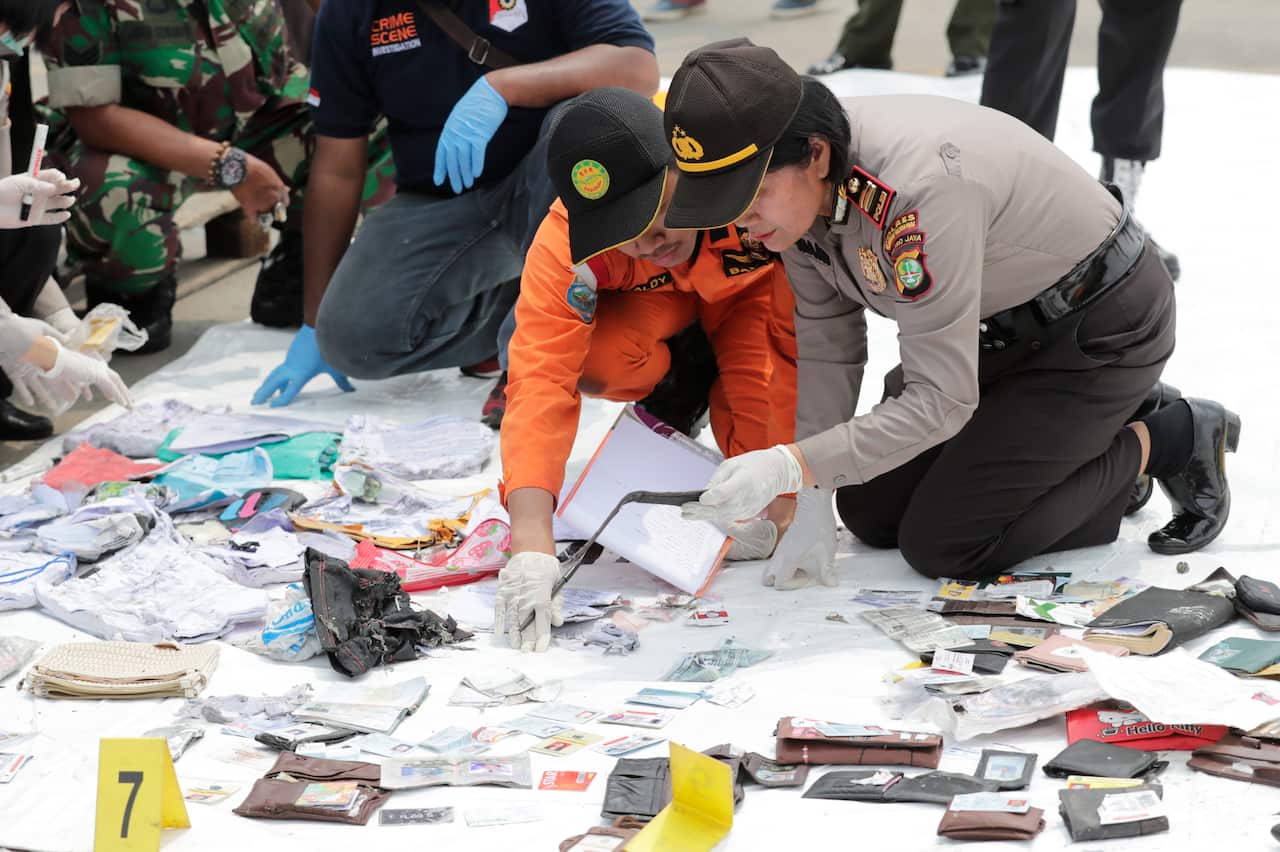 Indonesian rescuers collect and classify wreckage pieces and passenger belongings.