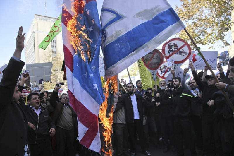 Iranian demonstrators burn representations of the U.S. and Israeli flags during a rally in front of the former U.S. Embassy in Tehran, Iran.